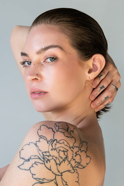 Side view of model wearing gold barbell earrings