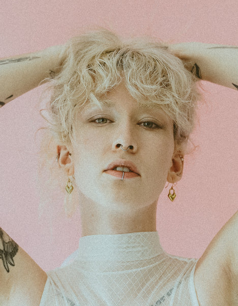 Model wearing heart charm earrings and mesh bodysuit