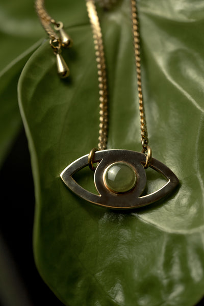 Close-up of gold eye pendant with green resin
