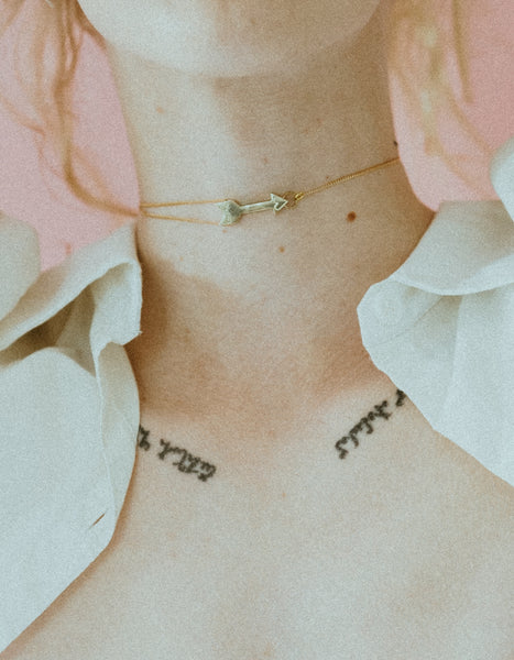 Close-up of models neck wearing arrow charm choker