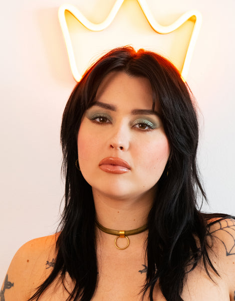 Model in front of a neon crown sign wearing a snake chain choker necklace