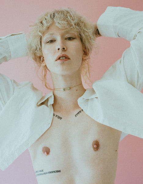 Model wearing gold arrow choker necklace and white open crop top blouse