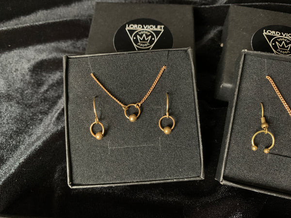 Captive barbell choker and earrings in a black gift box on a black velvet background