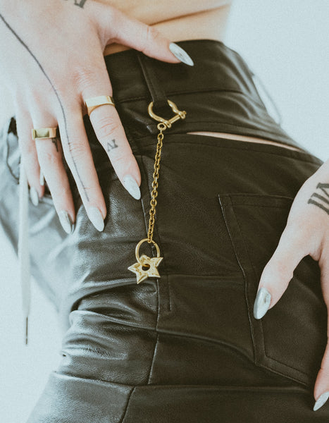 Close-up of spur keychain on models belt loop of black pleather pants