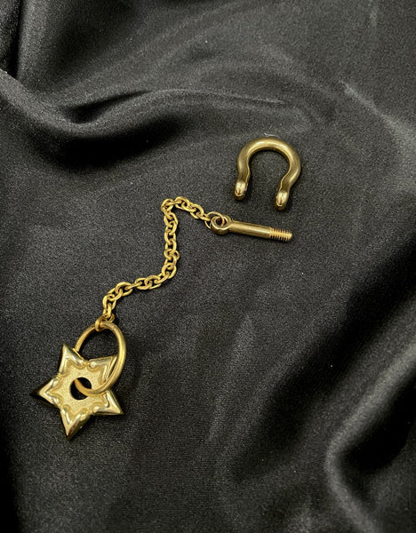 Close-up of open shackle of gold spur charm keychain on a black background