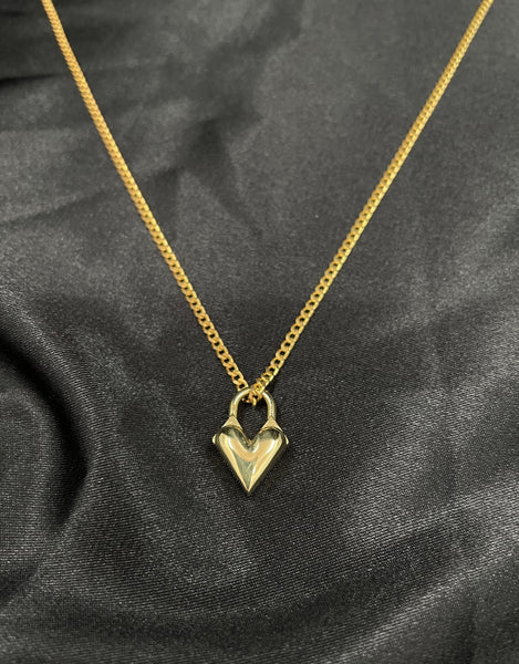 Close-up of gold heart locket charm of choker necklace on a black silk background