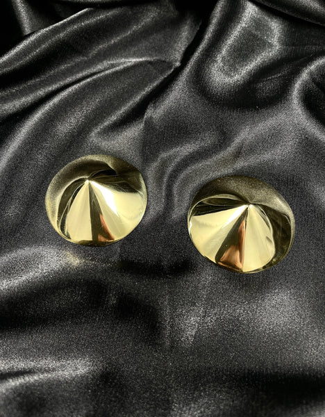 Round gold nipple pasties on a black silk background