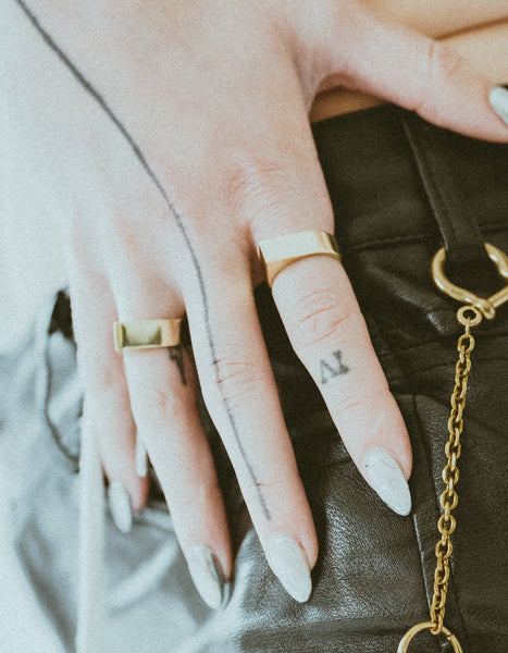 Close-up of models hand wearing two spiky gold rings