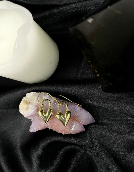 Heart locket earrings on a pink quartz stone and black silk background