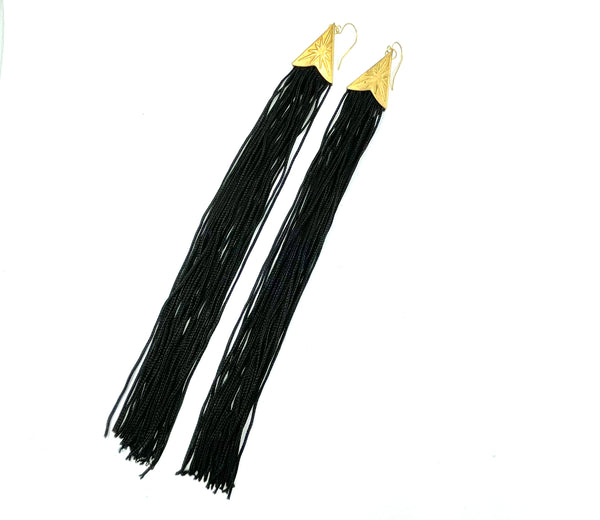 Black tassel earrings with brass star cap on a white background