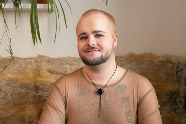 Model wearing diamond shaped onyx bolo tie and a beige mesh shirt