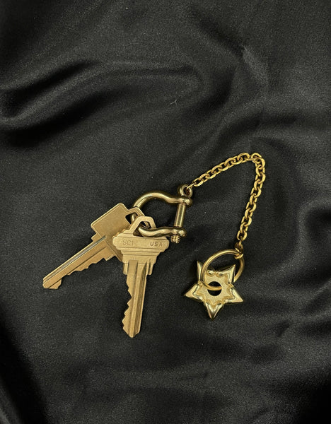 Gold spur keychain with keys on a black silk background