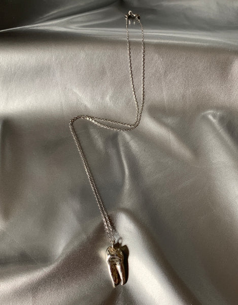 Sterling silver tooth charm choker on a shiny silver background