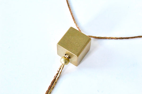 Close view of gold cube necklace pendant.