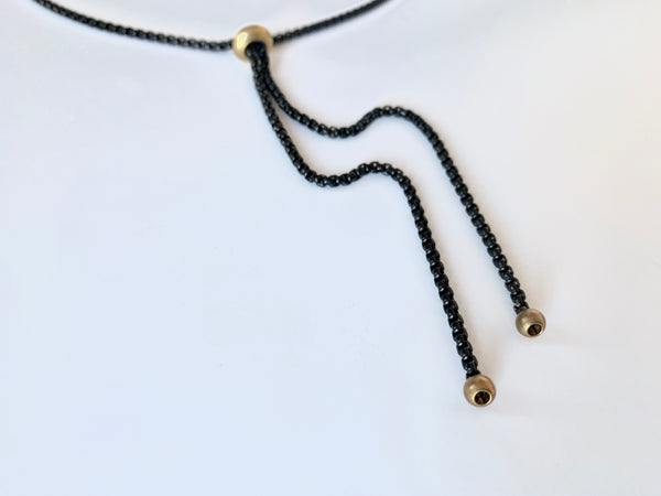 Gold bolo tie tips of black bolo tie necklace