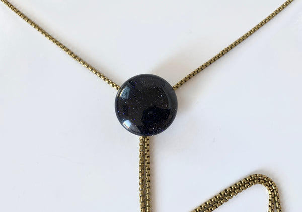 Close up of round blue goldstone pendant of bolo tie