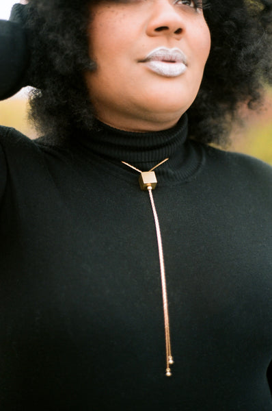 Gold cube bolo tie necklace on a model