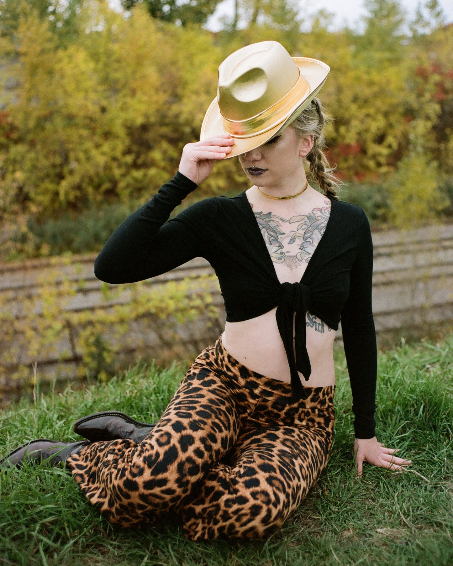 Model wearing gold choker and cowboy hat while sitting