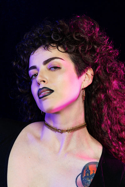 Model wearing brass hardware earrings and fishbone choker