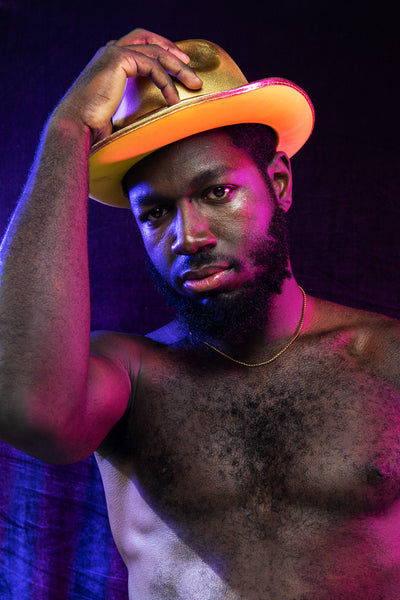 Model wearing rolo chain necklace, holding gold cowboy hat on his head