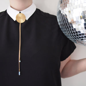 Model wearing gold bolo tie necklace and collared shirt