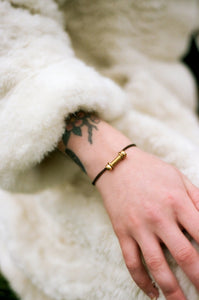 Black and gold barbell bracelet on model's wrist. 