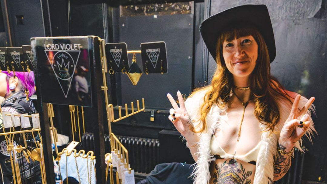 Person standing behind a display of jewelry at an event.