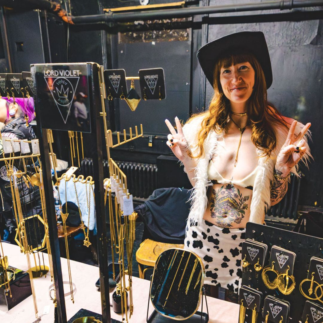 Person standing behind a display of jewelry at an event.