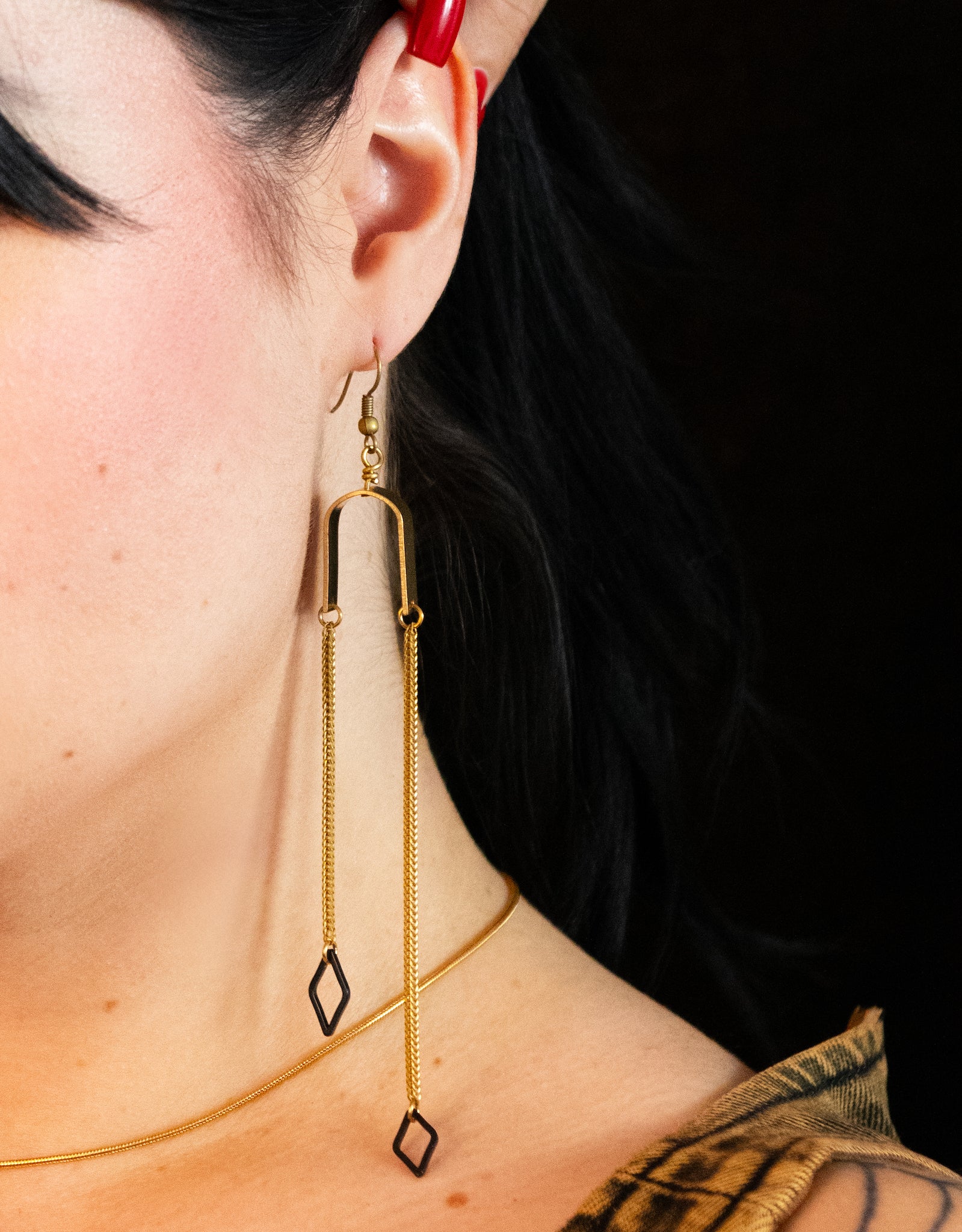 Close-up of triangle charm dangle earrings on a model