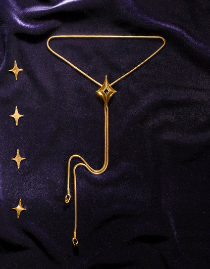 Gold snake chain bolo tie with star-shaped pendant on a dark blue velvet background