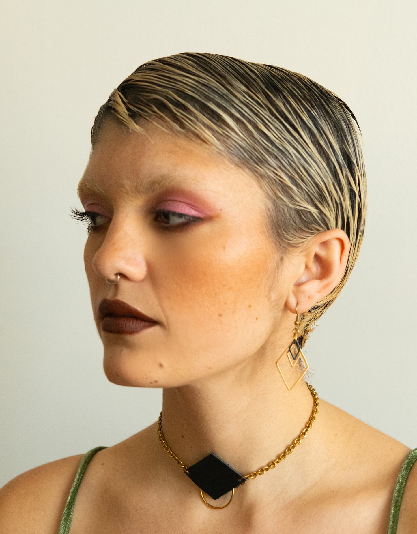 Model wearing black and gold diamond charm earrings and leather choker