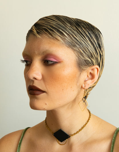 Model wearing black and gold diamond charm earrings and leather choker