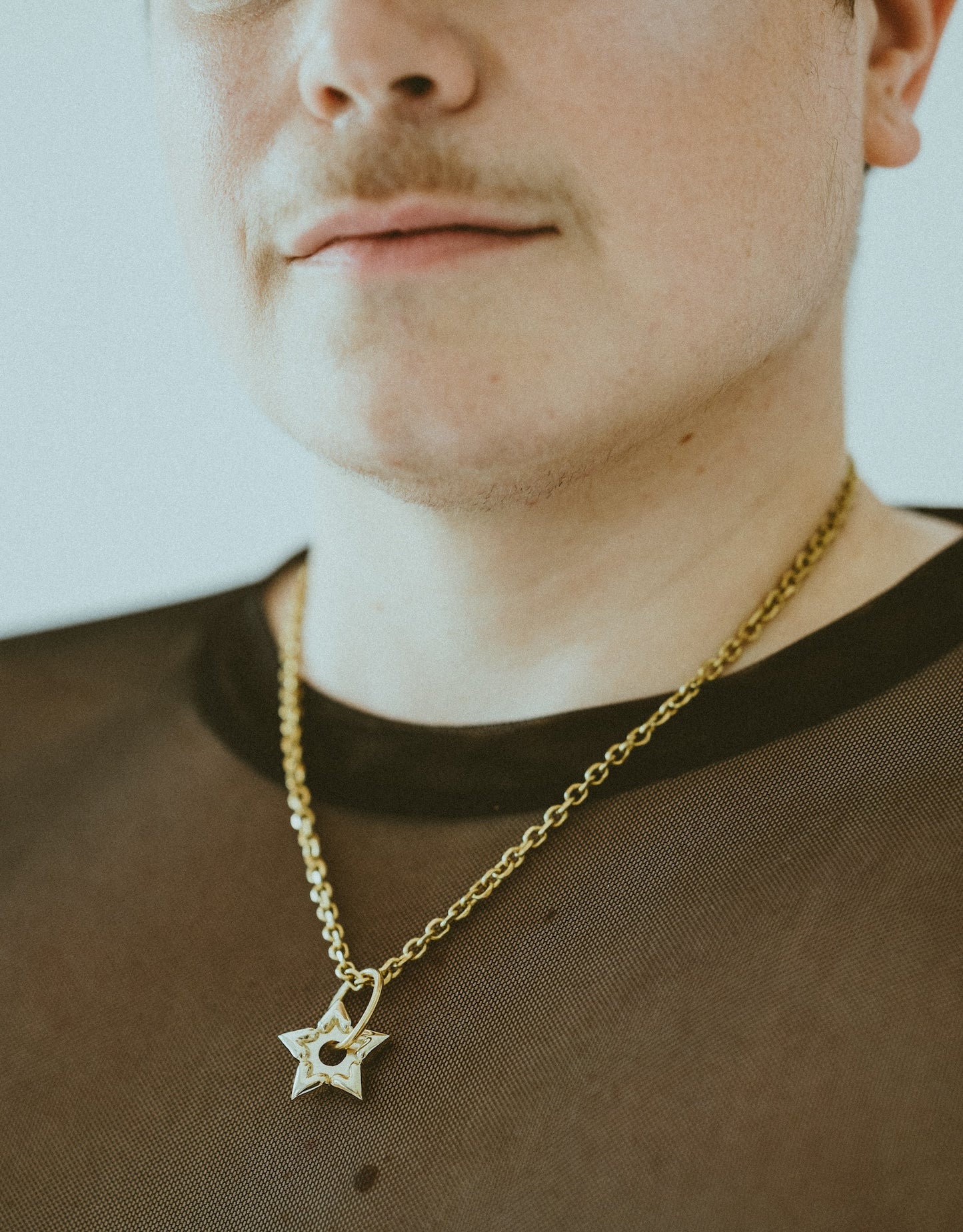 Close-up of model wearing gold spur choker and black mesh shirt