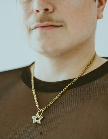 Close-up of model wearing gold spur choker and black mesh shirt
