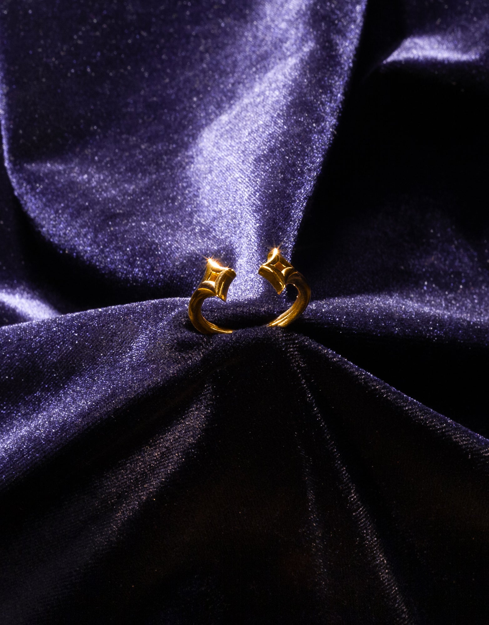 A gold star ring upright on a dark blue velvet background