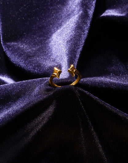 A gold star ring upright on a dark blue velvet background