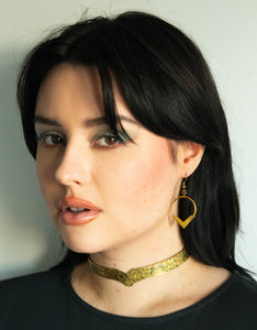 Model wearing gold choker with floral pattern and gold pointed hoop earrings