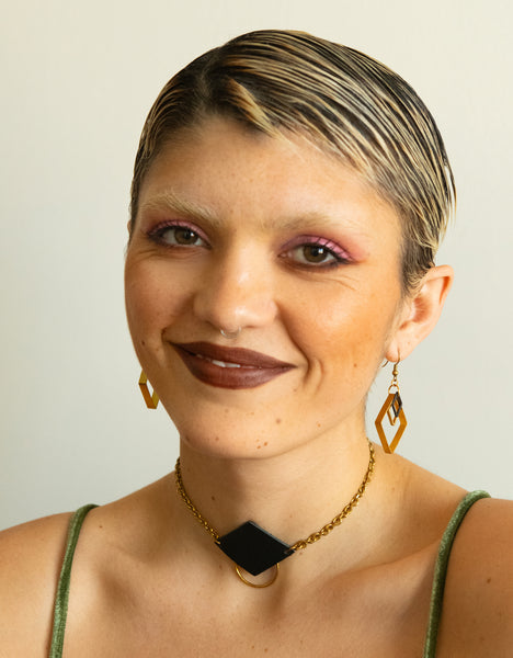 Model wearing leather choker necklace and triangle charm earrings
