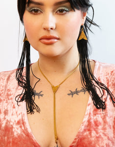 Model wearing sunburst bolo tie, matching tassel earrings and a pink velvet top