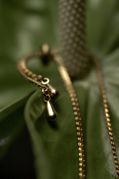 Close-up of brass teardrop charms of gold bracelet