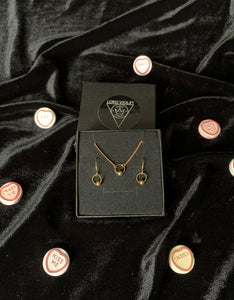 Captive barbell choker and earrings in a black gift box, surrounded by candy hearts on a black velvet background