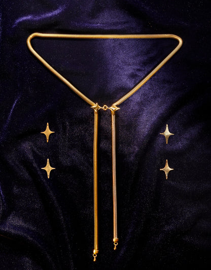 Gold bolo tie necklace with star pendants on a dark blue velvet background with brass stars