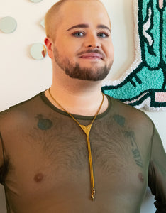 Model wearing gold triangle bolo tie with a starburst pendant, foxtail chain and bullet bolo tie tips and a green mesh shirt