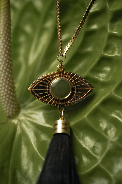 Close-up of gold eye pendant with green resin, on a leaf