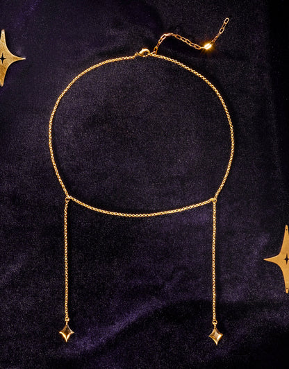 Gold choker necklace with hanging star pendants, surrounded by stars on a dark blue velvet background