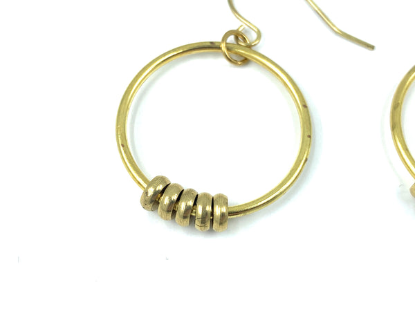 Close-up of beaded gold hoop earrings on a white background