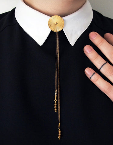 Black and gold bolo tie necklace on a model