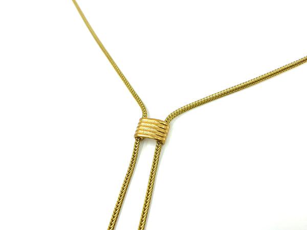 Close-up of slide bead of gold bolo tie necklace on a white background