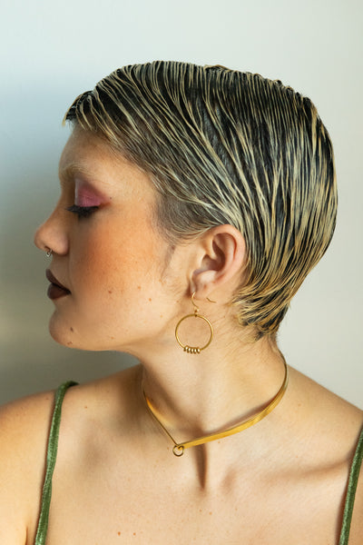 Side view of model wearing gold bead hoop earrings and gold choker collar