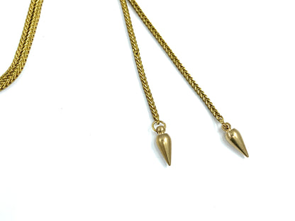 Close-up of brass spike bolo tie tips on a white background